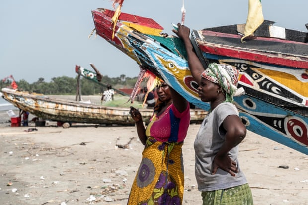 Fish traders Isatou Darboe (left) and Matida Jobewait for fishing boats to arrive, in Gunjur village
