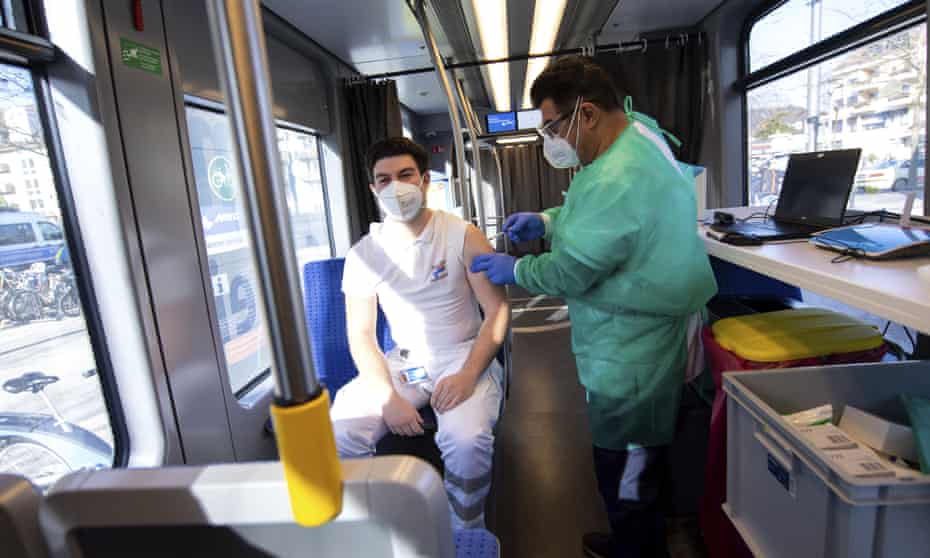 A doctor administers a Covid-19 jab to a ambulance service worker in a mobile vaccination unit in Munich