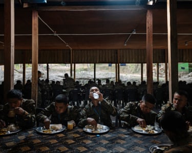 The rebels sit at a table with plates of food, eating with their hands