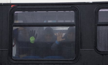 Men in coats with hoods pulled up and winter gloves with their hands raised to the colorful window of a bus.
