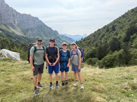 A man, a woman and two teenage boys on a grassy area in the foothills of a mountain