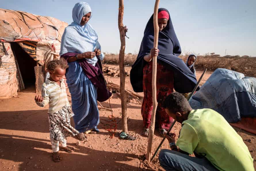 The Abdi Rahman family place wooden poles in the ground as they set up shelter in a camp for displaced people in Somaliland