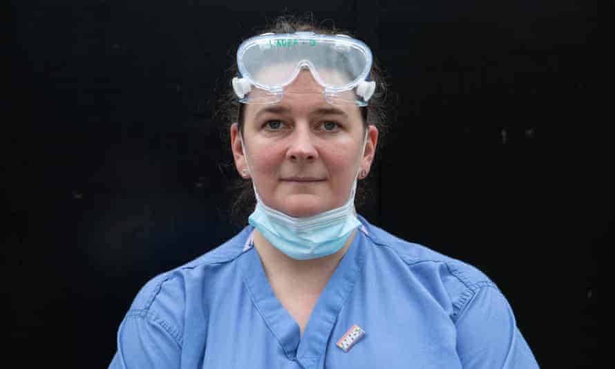 Head-and-shoulders portrait of Laura Duffell in her blue NHS uniform, with protective goggles pushed up on to her forehead and her mask round her neck