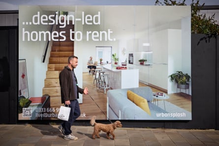 A man walks a curly haired dog past a New Islington billboard advertising homes to rent