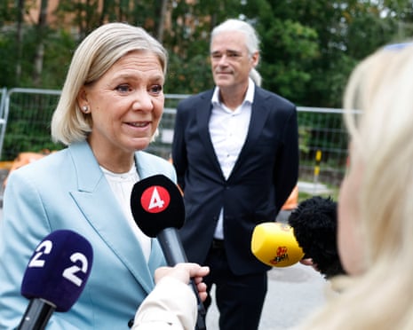 Sweden’s Social Democratic party leader Magdalena Andersson gives an interview as her husband, Richard Friberg, looks on in front of a polling in Nacka during Sweden’s general election.