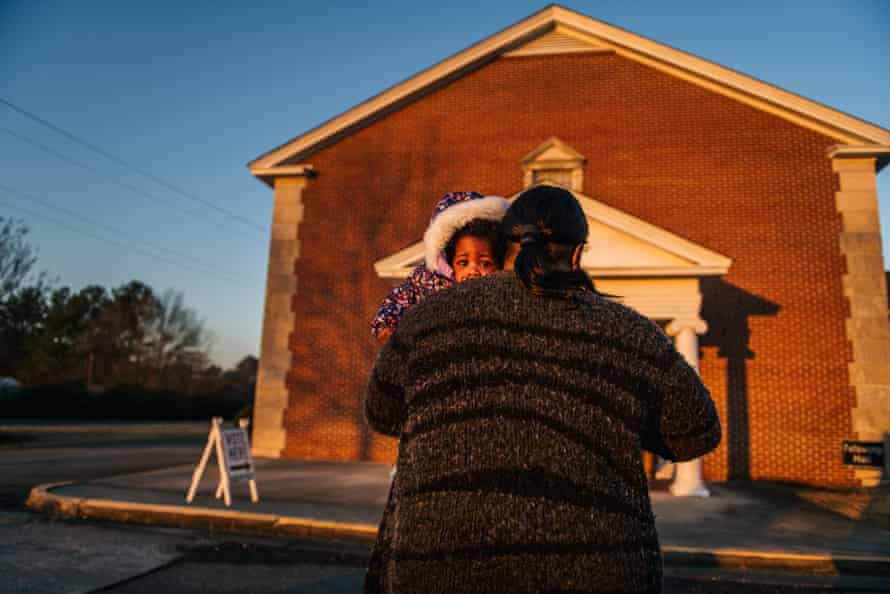 TaRean Howard carries her granddaughter into a polling station at the Garden Lakes Baptist Church on Tuesday in Rome, Georgia.