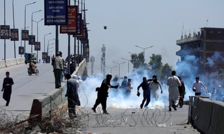Teargas and people running near flyover with barbed wire in foreground