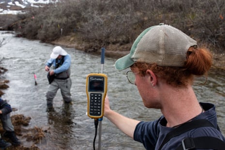 two men in hats holding scientific equipment standing in a river measuring something two men in hats holding scientific equipment standing in a river measuring something