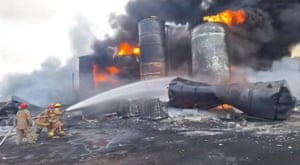 Three firefighters tackle blaze, with metal cylinders alight