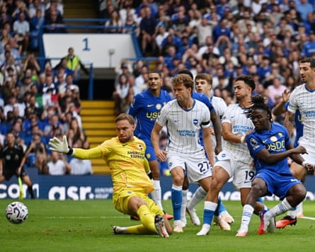The Chelsea midfielder Roméo Lavia (second right) watches after poking the ball past the Brighton goalkeeper Bart Verbruggen (left) to score his team's first goal in their 4-3 Premier League win.