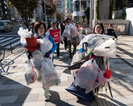 Two women loaded up with large amounts of rubbish in bags on the street