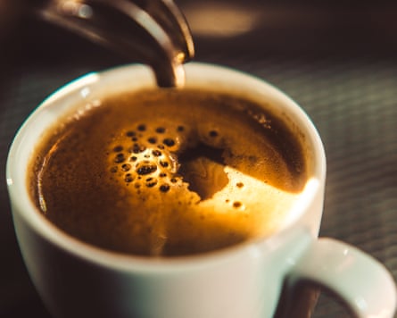 Espresso pours from a machine spout into a white cup, forming a crema-topped shot