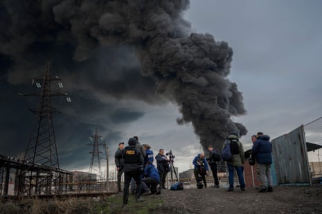 Journalists and residents watch the smoke from the strike