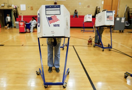 Voters stand inside rolling booths marked "Vote" in a New York gymnasium during early voting