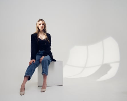 A full length portrait of a young woman sitting on the cube with lights ands shadows.