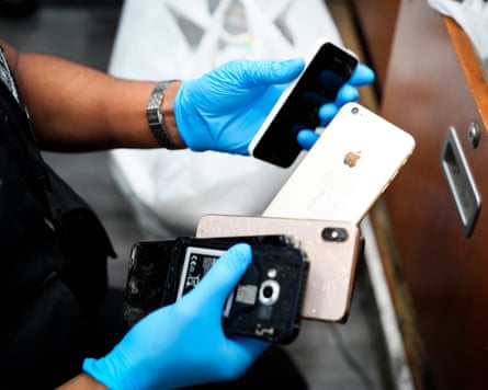 A close up of a police officer wearing blue latex gloves as they handle suspected stolen devices in London
