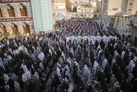 Crowds of veiled women gathered in a square, praying