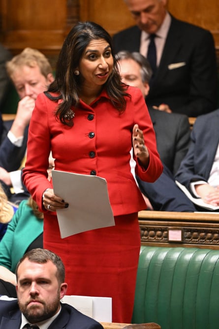 Suella Braverman in a red suit standing up on the back benches and gesturing as she speaks