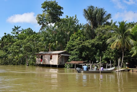 Rainforest, shack and boat on muddy river in Brazil