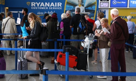 Travellers queue at a Ryanair customer service desk at Stansted airport.