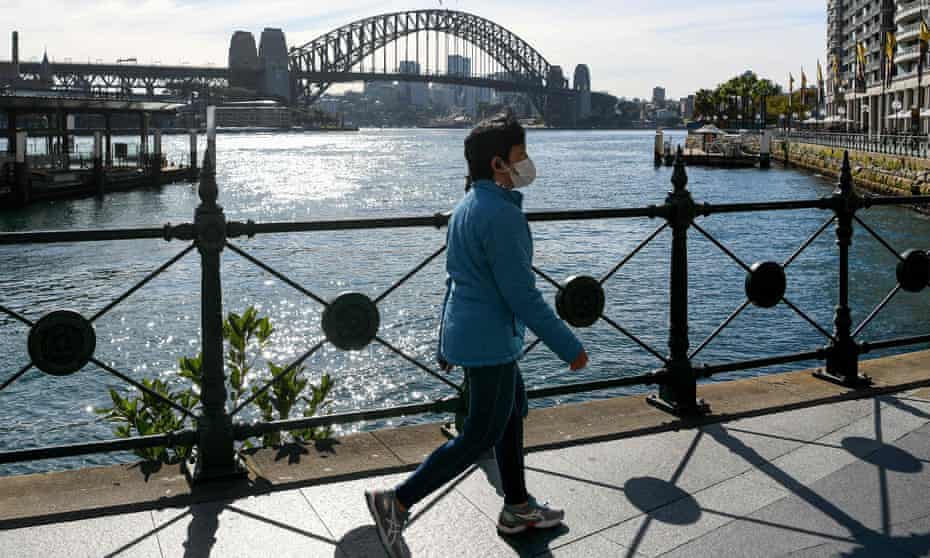 A woman wearing a face mask walks along a quiet Circular Quay in Sydney