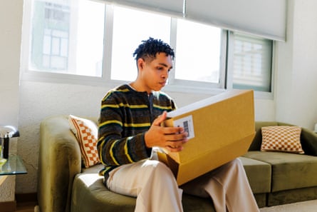 Man sitting on sofa opening package