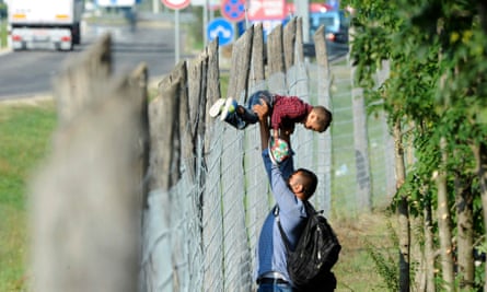 A family hop over the fence at the migration centre in Roszke, Hungary.