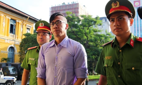 William Anh Nguyen is escorted by policemen to a courtroom for his trial in Ho Chi Minh City on Friday.
