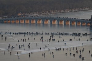 Overhead view of people riding sleds, with the 17-arch bridge over the lake behind