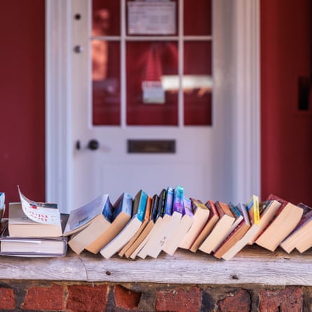 Lots of books placed in front of the door to a small business store in the UK.