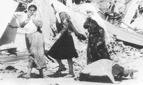 Palestinian women pass a victim of the massacres in the Palestinian refugee camp of Sabra, in West Beirut in 1982.