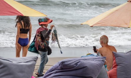 'A little annoying': Concern and skepticism in Bali over ban on sex outside marriage | Indonesia 1 A souvenir seller walks among tourists on a beach in Canggu.