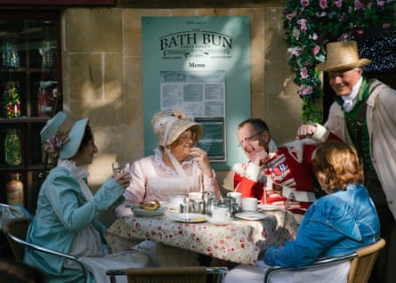 People in period dress sit at a table having tea