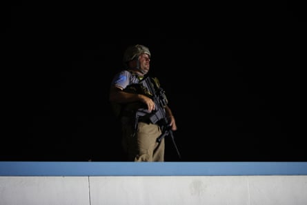 An armed civilian stands on a roof during protests over the shooting of Jacob Blake by a police officer in Kenosha, Wisconsin.