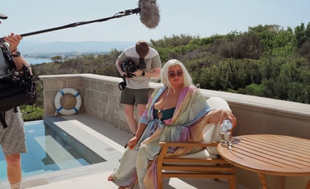 Gemma Collins sits on a sun terrace next to a pool, while a cameraman and boom operator stand nearby