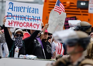 a person holds a sign that reads ‘American hypocrisy’
