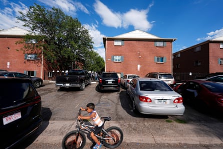 A child rides a bike in the parking lot of an apartment complex