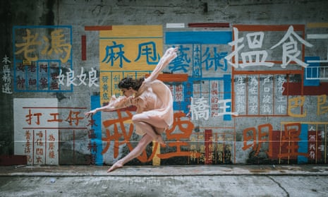 A dancer from OTC Graffitt performs in front of street art in Hong Kong.