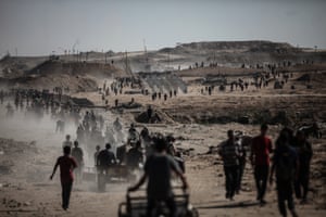 A large number of Palestinian people silhouetted against a landscape, in the foreground, and into the distance