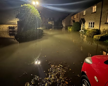 Flood water fills the road in front of a row of old stone terraced village homes