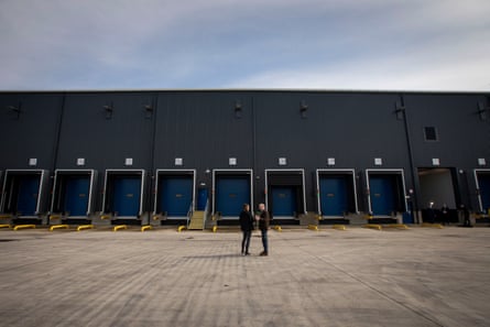 Long-distance view of the outdoor lorry ports. The site is empty but for the two people standing in the centre.