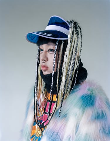 Fashion student Shoshi Doi wears a blue visor cap over long braided hair extensions, with facial piercings