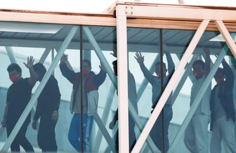 men with their hands up walking through an airport corridor