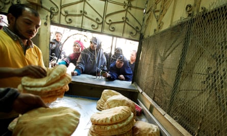 Women wait for flatbread at a hatch in a bakery