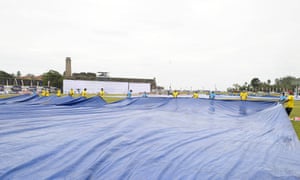 Ground staff cover the pitch.