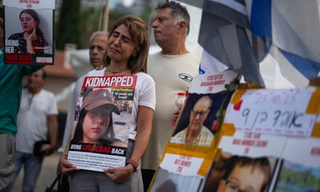 An Israeli woman cries as she holds a photo of a woman who was kidnapped.