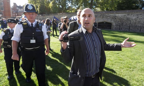 Blogger Graham Phillips is escorted away by police officers after he disrupted a press conference opposite the Houses of Parliament in October 2018. 