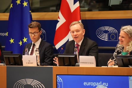 he sits on a panel in front of a union jack flag.