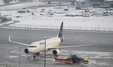 A snowplough drives past a plane at Munich airport after all incoming and outgoing flights were cancelled