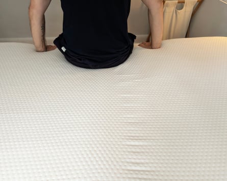 The reviewer’s husband testing the edge support of the Emma Hybrid Premium mattress.